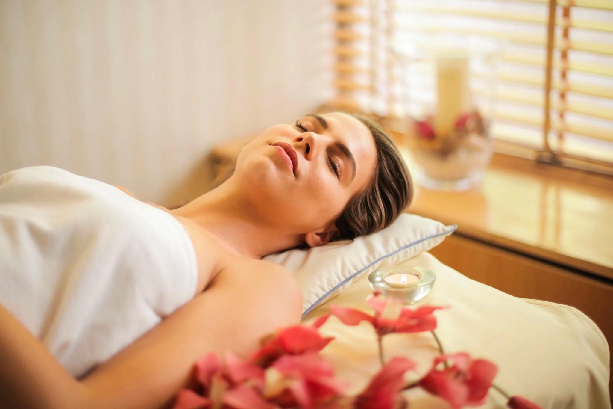 A person lays on a massage table looking relaxed and happy.